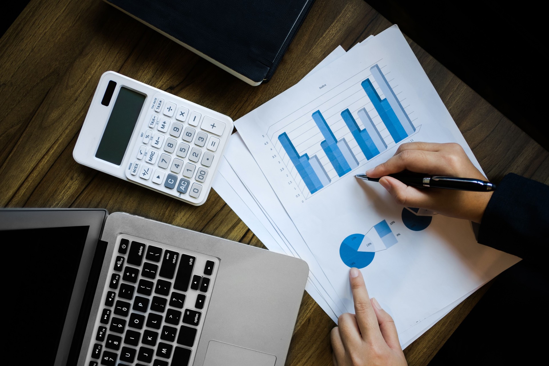 image of bookkeeper /  financial inspector calculating on investment data with documents and laptop in dark office room
